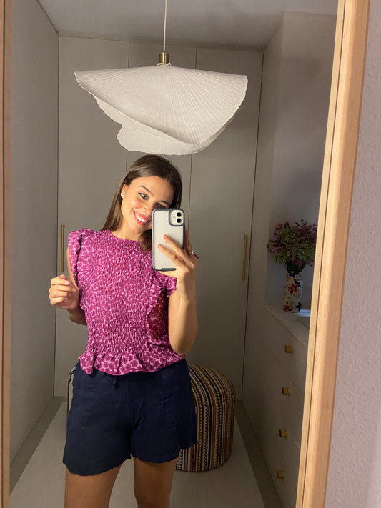 Blusa en tono rosados con nido en la parte delantera y volantes en las mangas.  Composición: 96 % poliéster, 4 % elastano.  Hecho en Italia.  La modelo mide 163 cm.